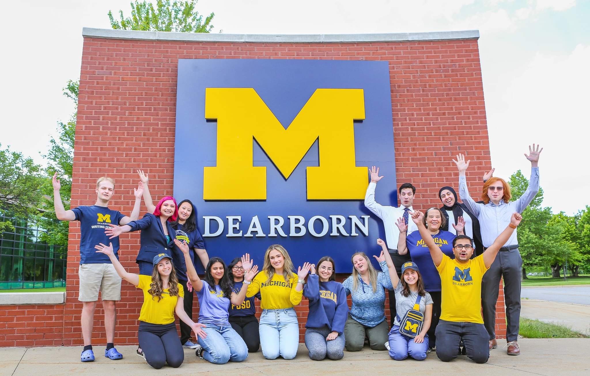 UM Dearborn students in front of UoM logo